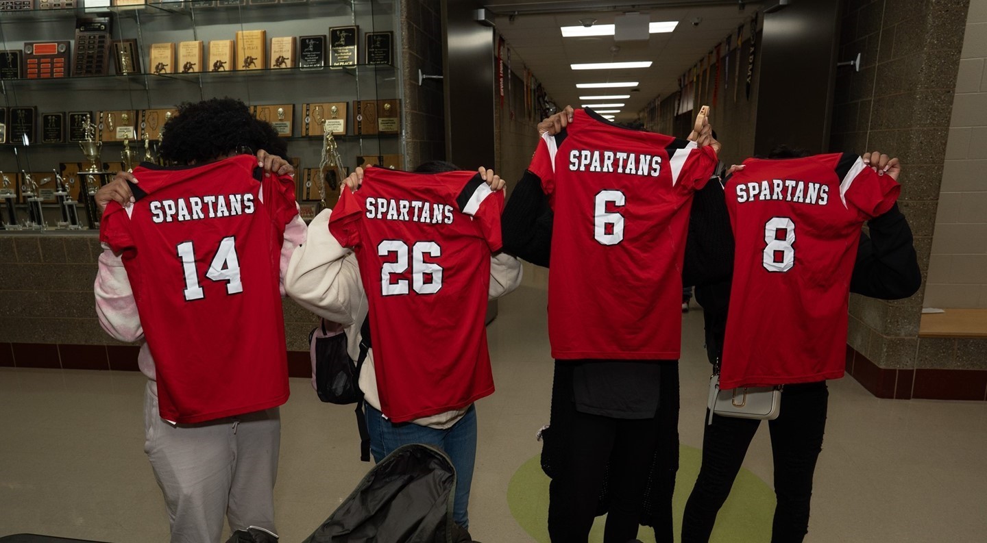 Boys basketball team holding red jerseys up