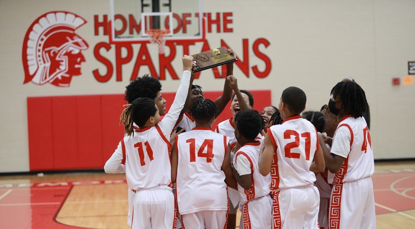 Boys basketball team raising championship plaque